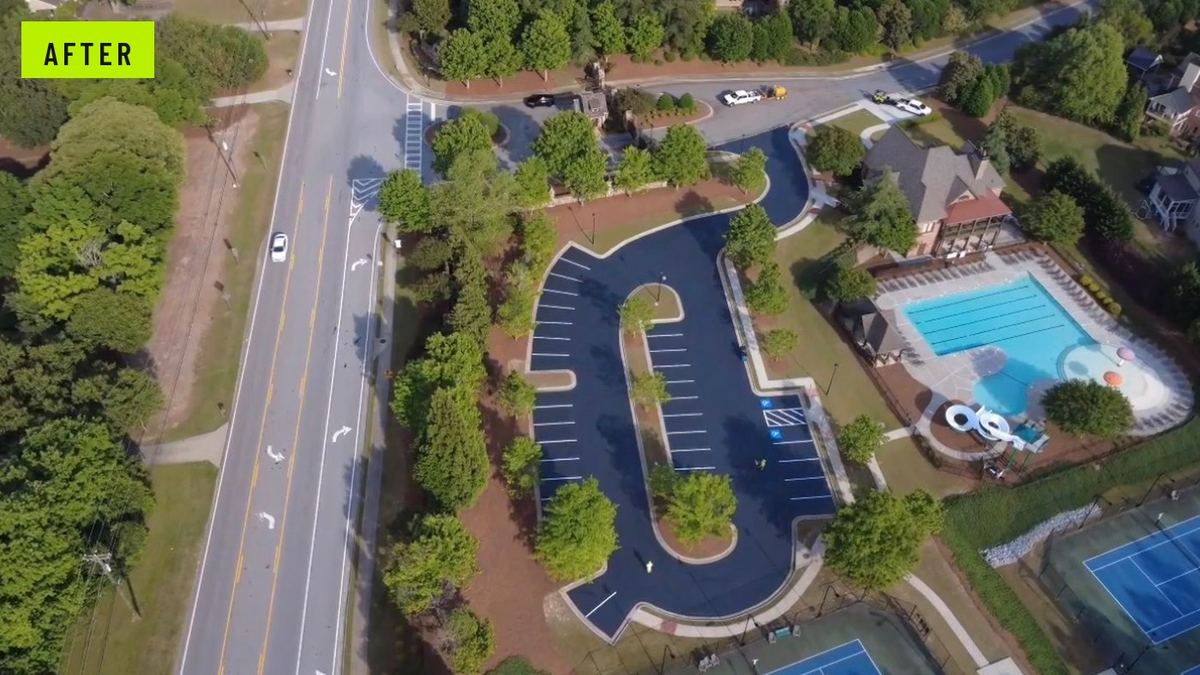 After: the same amenity lot sealcoated deep black with bright new stall lines and blue ADA stalls near the pool entrance.